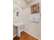 Charming powder room featuring hardwood floors, a pedestal sink, and decorative framed artwork at 511 Duque Rd, Lutz, FL 33549