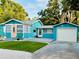 Beautiful blue house with a pink front door, lush green lawn, and a detached garage at 5130 Pine Grove S Ter, Gulfport, FL 33707