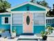 Close-up of a charming blue house featuring a pink front door and well-maintained landscaping at 5130 Pine Grove S Ter, Gulfport, FL 33707