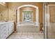 Bright bathroom featuring a soaking tub with arched window, white cabinets, and glass-enclosed shower at 5283 Bevens Ave, Spring Hill, FL 34608