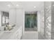 Bright bathroom featuring double sinks, a large mirror, and a walk-in shower with decorative tiling at 5884 51St S St, St Petersburg, FL 33715
