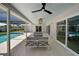 Inviting covered patio boasts travertine floors, fan, and comfortable seating, overlooking a screened-in pool and lush landscaping at 5884 51St S St, St Petersburg, FL 33715