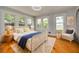 Bright bedroom features three large windows, hardwood floors, a wicker bed, and neutral decor with a pop of blue at 6408 N Central Ave, Tampa, FL 33604