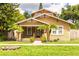 Charming home featuring a cozy front porch, well-maintained lawn, and lush landscaping with mature trees at 6408 N Central Ave, Tampa, FL 33604