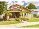 Charming home featuring a cozy front porch, well-maintained lawn, and lush landscaping with mature trees at 6408 N Central Ave, Tampa, FL 33604
