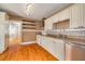 Well-lit kitchen showcasing wood floors, white cabinets, modern appliances, and a view into an adjacent room at 6408 N Central Ave, Tampa, FL 33604