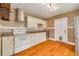 Functional kitchen featuring white appliances, matching cabinetry, mosaic tile backsplash, and hardwood flooring at 6408 N Central Ave, Tampa, FL 33604
