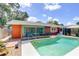 A beautiful pool with sun-washed deck is bordered by a bright orange home exterior and verdant trees at 6865 Circle Creek Dr, Pinellas Park, FL 33781
