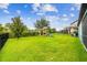 A green backyard featuring a black fence, a tree and a view of the rear of the house at 9816 Ivory Dr, Sun City Center, FL 33573