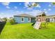 A green backyard featuring a black fence, play set, and a view of the rear of the house at 9816 Ivory Dr, Sun City Center, FL 33573