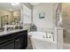 A tub and vanity with granite countertop in a well-lit bathroom at 9816 Ivory Dr, Sun City Center, FL 33573