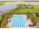 Aerial view of a large community pool with lounge chairs, tennis courts, and a picturesque lake nearby at 9816 Ivory Dr, Sun City Center, FL 33573