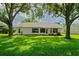 Rear house exterior featuring a well-maintained lawn and mature landscaping at 11412 Alden Ct, Hudson, FL 34667