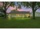 Back exterior view featuring a lush lawn with mature landscaping; a perfect outdoor retreat at dusk at 11412 Alden Ct, Hudson, FL 34667