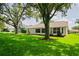 Back exterior of the house with a well-manicured lawn, mature shade trees, and view of the screened lanai at 11412 Alden Ct, Hudson, FL 34667