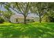 Rear exterior showing the well-maintained lawn, shade trees, and a glimpse of the home's roof at 11412 Alden Ct, Hudson, FL 34667