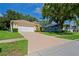 Home exterior featuring a long driveway leading to a two-car garage and well-maintained landscaping at 11412 Alden Ct, Hudson, FL 34667