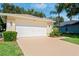Home exterior featuring a two-car garage, large driveway, manicured landscaping, and clear address at 11412 Alden Ct, Hudson, FL 34667