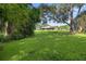 Lush backyard with a screened pool enclosure and mature trees in the background at 1357 Dinsmore Ct, New Port Richey, FL 34655