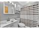 Clean bathroom with white fixtures, a shower with curtain, and medicine cabinet at 1357 Dinsmore Ct, New Port Richey, FL 34655