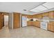 The bright kitchen features classic wood cabinets, white appliances, and durable tiled floors at 1357 Dinsmore Ct, New Port Richey, FL 34655