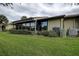 Back exterior view of house, including an enclosed sunroom, lawn, and landscaping at 140 Dale Pl, Oldsmar, FL 34677