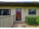 Charming front entryway with a bright red door, decorative plants, and traditional exterior lighting at 140 Dale Pl, Oldsmar, FL 34677