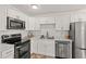 A bright and modern kitchen featuring stainless steel appliances, white cabinets and marble countertops at 1743 Fulton Ave, Clearwater, FL 33755