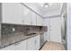 Galley kitchen with white cabinets, granite countertops, stainless steel appliances, and neutral tile floors at 1813 Bough Ave # B, Clearwater, FL 33760