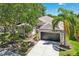 Beautiful home exterior featuring a well-manicured lawn, mature trees, and a two-car garage at 19113 Golden Cacoon Pl, Lutz, FL 33558