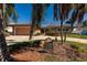 Charming single-story home featuring a spacious driveway and lush landscaping with mature palm trees at 208 Bath Club N Blvd, North Redington Beach, FL 33708