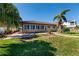 View of the home's rear exterior with a lush green lawn, brick patio, and multiple large windows at 208 Bath Club N Blvd, North Redington Beach, FL 33708