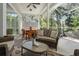 Enclosed patio includes ceiling fan, wicker furniture, and view of the wooded backyard at 2182 Trevor Rd, Palm Harbor, FL 34683