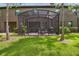 Beautiful backyard featuring a screened-in patio, lush green lawn, and mature trees at 28568 Tranquil Lake Cir, Wesley Chapel, FL 33543