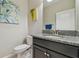 Charming half bathroom with decorative paintings, granite countertop, and a dark wood cabinet at 28568 Tranquil Lake Cir, Wesley Chapel, FL 33543