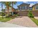 A quaint two-story townhome boasts a brick driveway, manicured landscaping, and a welcoming facade at 28568 Tranquil Lake Cir, Wesley Chapel, FL 33543
