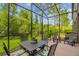 Screened-in patio with a dining table, offering a serene outdoor space surrounded by lush greenery at 28568 Tranquil Lake Cir, Wesley Chapel, FL 33543