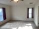 Bright, spacious bedroom with neutral carpet, ceiling fan, and two windows with vertical blinds and burgundy drapes at 29702 Tee Shot Dr, San Antonio, FL 33576