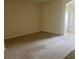 Open living room with neutral carpet and light walls, and a glimpse of a tiled hallway and doorway at 29702 Tee Shot Dr, San Antonio, FL 33576