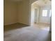 Spacious living room with neutral carpet and paint, with a tiled entry visible through an arched doorway at 29702 Tee Shot Dr, San Antonio, FL 33576