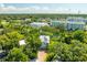 Aerial view of a two-story home with solar panels nestled among lush trees and a community in the distance at 321 Barbara Cir, Belleair, FL 33756