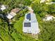 Aerial view of a modern home featuring a solar panel roof and lush greenery surrounding the property at 321 Barbara Cir, Belleair, FL 33756