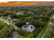 Sunset aerial view of home featuring solar panels, mature trees, and lush surrounding neighborhood at 321 Barbara Cir, Belleair, FL 33756