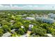 Aerial view of a two-story home with solar panels nestled among lush trees and a community in the distance at 321 Barbara Cir, Belleair, FL 33756
