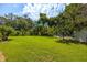Spacious backyard with lush grass, mature trees, and sturdy fencing, offering privacy and a serene outdoor experience at 321 Barbara Cir, Belleair, FL 33756