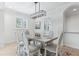 Bright dining room featuring modern chandelier, neutral color scheme, and windows with plantation shutters at 321 Barbara Cir, Belleair, FL 33756