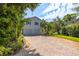Two-story home featuring a double garage and a brick paved driveway lined with lush landscaping at 321 Barbara Cir, Belleair, FL 33756