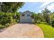 Two-story home featuring a double garage and a brick paved driveway lined with lush landscaping at 321 Barbara Cir, Belleair, FL 33756