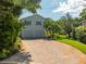Two-story home with two car garage, brick driveway, blue shutters and lush landscaping at 321 Barbara Cir, Belleair, FL 33756