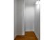 Hallway with wood flooring, white walls, crown molding and access to ceiling storage at 321 Barbara Cir, Belleair, FL 33756